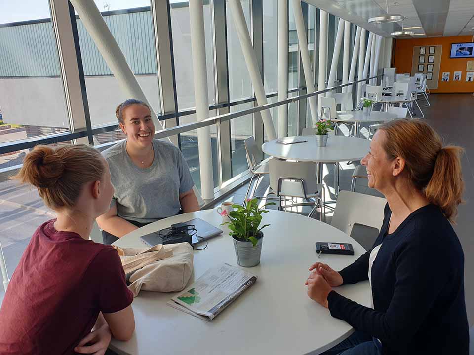 Examenshandledare Henriette Eriksson samtalar med studerande Frida Nordlund och Essi Weckström.